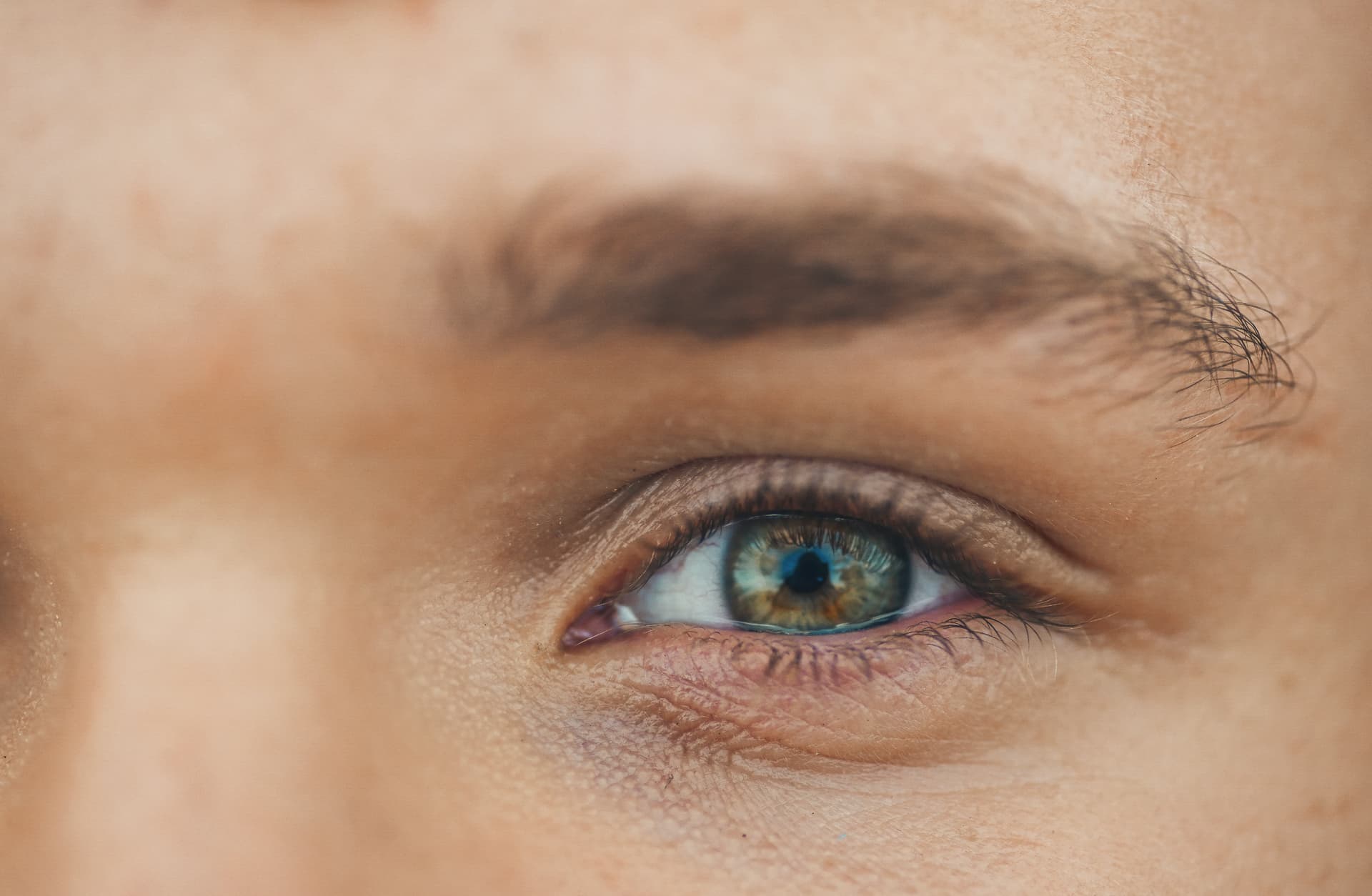 Close-up of a person's hazel eye with detailed lashes and eyebrow visible.