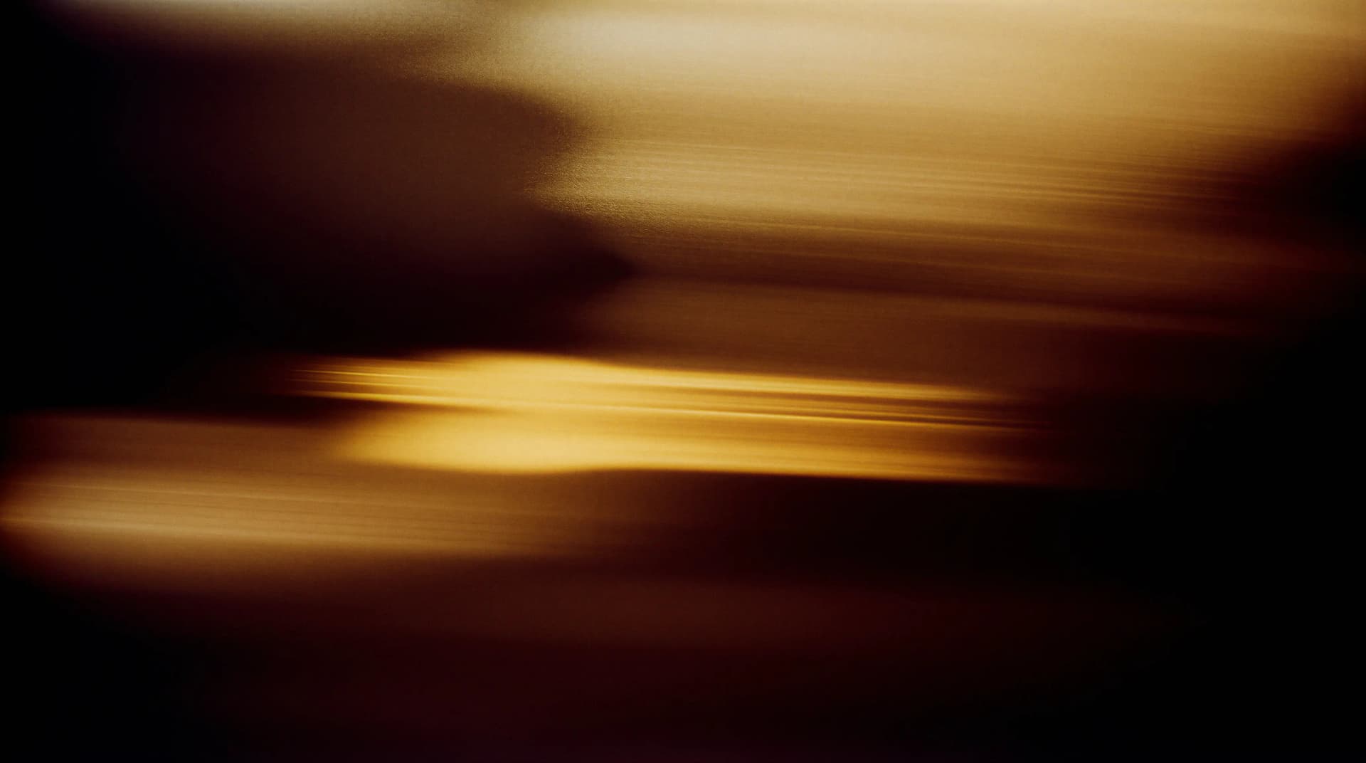 Abstract image with blurred golden and brown horizontal streaks, creating a dynamic, flowing effect.
