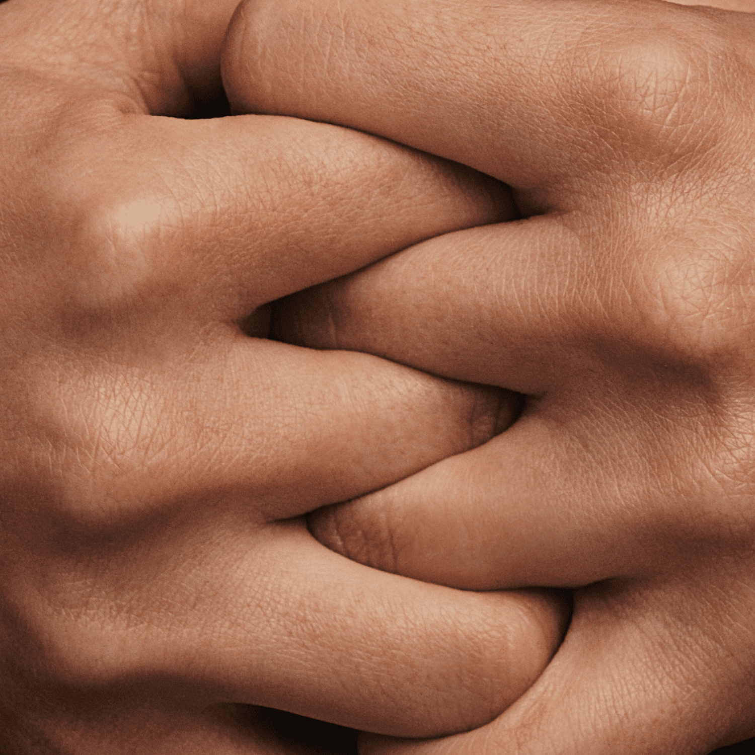 Two hands clasped tightly together, showing fingers interlocked, with detailed skin texture visible.