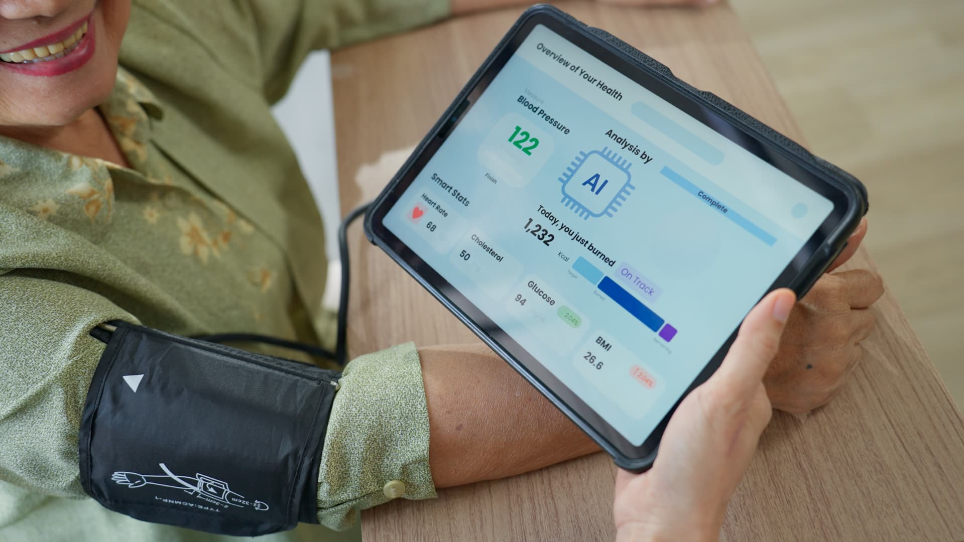 Smiling person holds a tablet displaying health data, with a blood pressure cuff on their arm showing a reading of 122/82 mmHg.