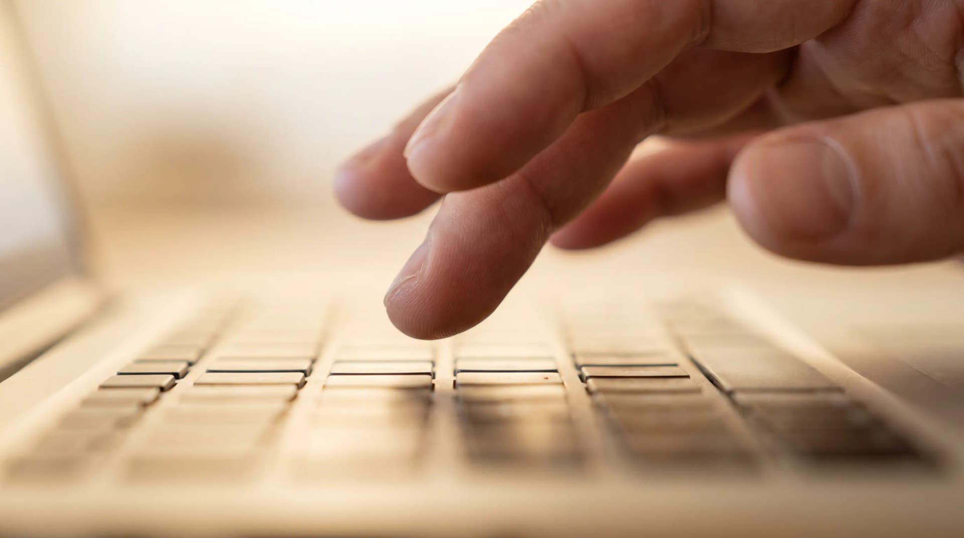 Close-up of fingers hovering over a laptop keyboard, ready to type, with soft lighting and a shallow depth of field.