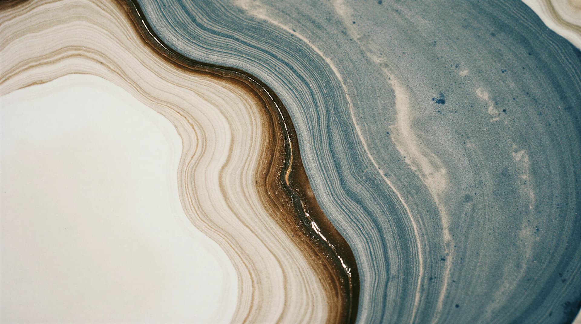Abstract image of wavy, layered patterns in beige, brown, and blue tones, resembling a geological cross-section or marble texture.