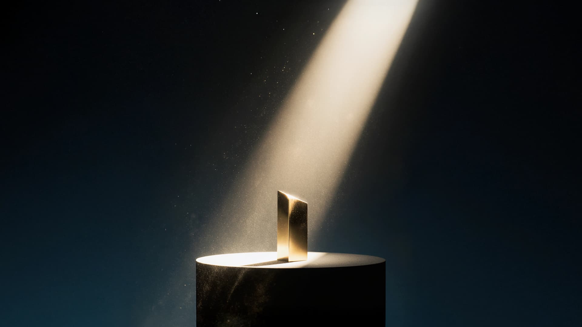 Golden award in spotlight on a dark cylindrical pedestal against a dark background, with light particles visible in the beam.
