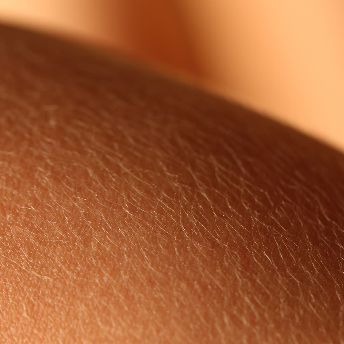 Close-up of dry skin, showing a textured surface with small lines and a warm, soft lighting.