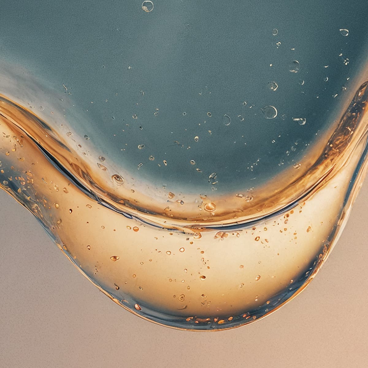 Close-up of blue and gold liquid bubbles against a gradient background, forming abstract shapes with captured air.