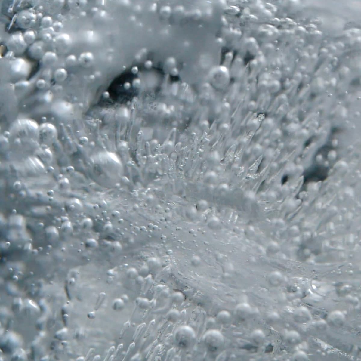 Close-up of ice with trapped air bubbles and intricate frozen patterns, creating a textured and crystalline appearance.