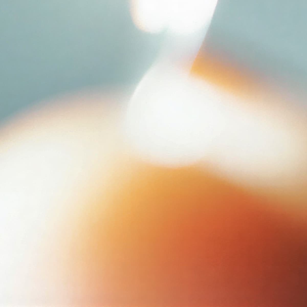 Abstract image with soft, blurred colors in warm orange, white, and blue tones, creating a serene, dreamy atmosphere.