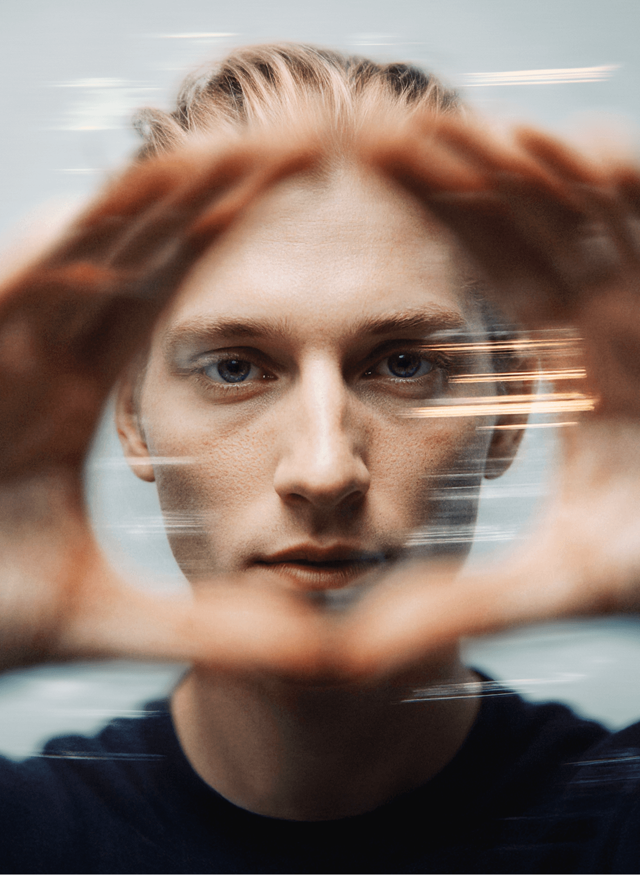 A focused close-up of a person looking through a circular hand gesture, with a motion blur effect surrounding their face, creating dynamic lines.