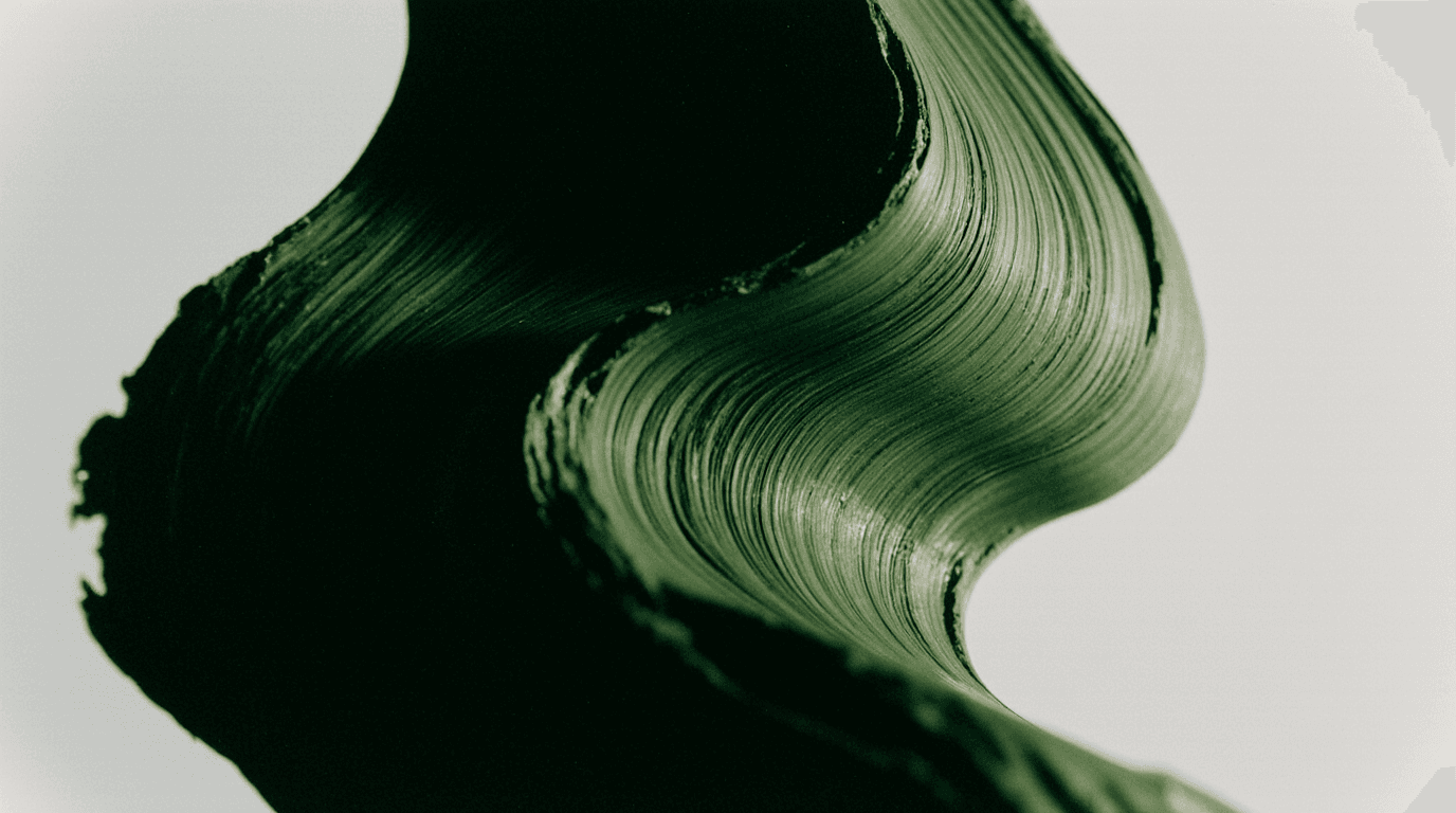 Close-up of a green plant leaf with a smooth, curving texture against a light background.