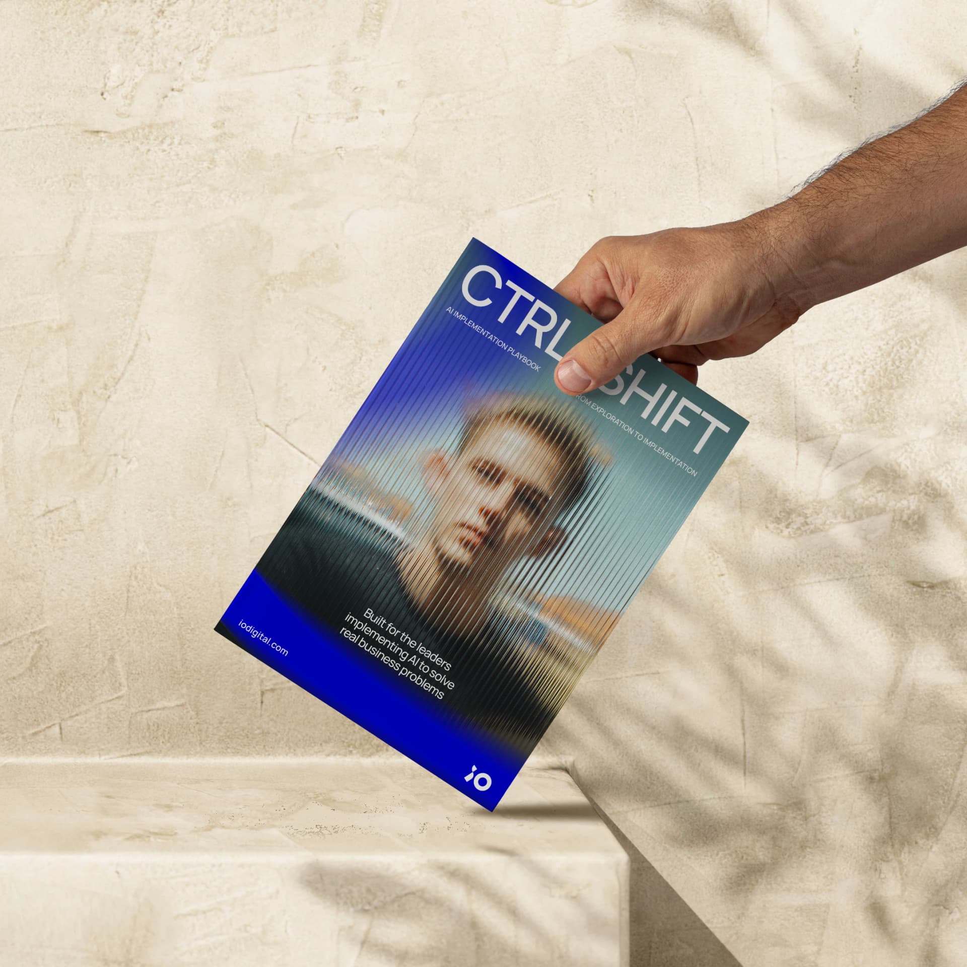 A hand holding a magazine titled “CTRL+SHIFT” with a blurred image of a person on the cover, set against a textured beige background.
