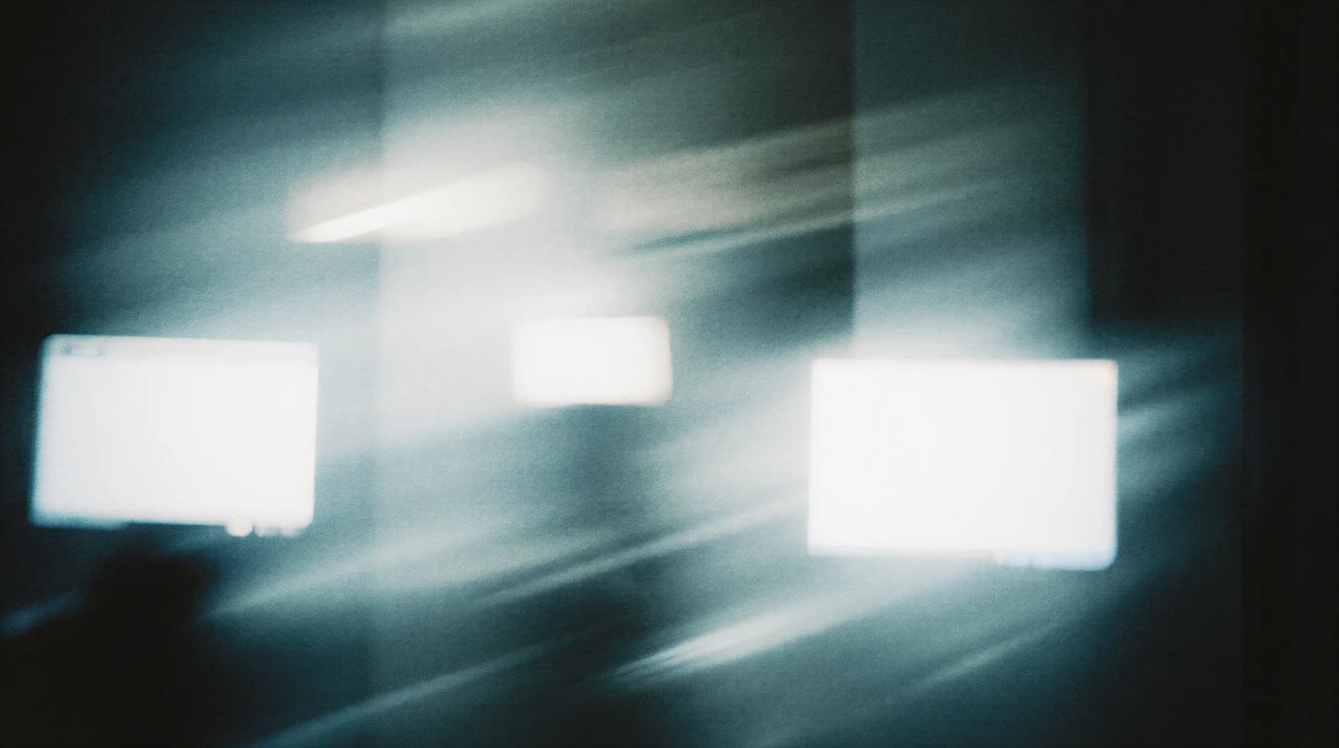 Blurred abstract image with bright, glowing rectangles against a dark background, creating a dreamy, ethereal effect.