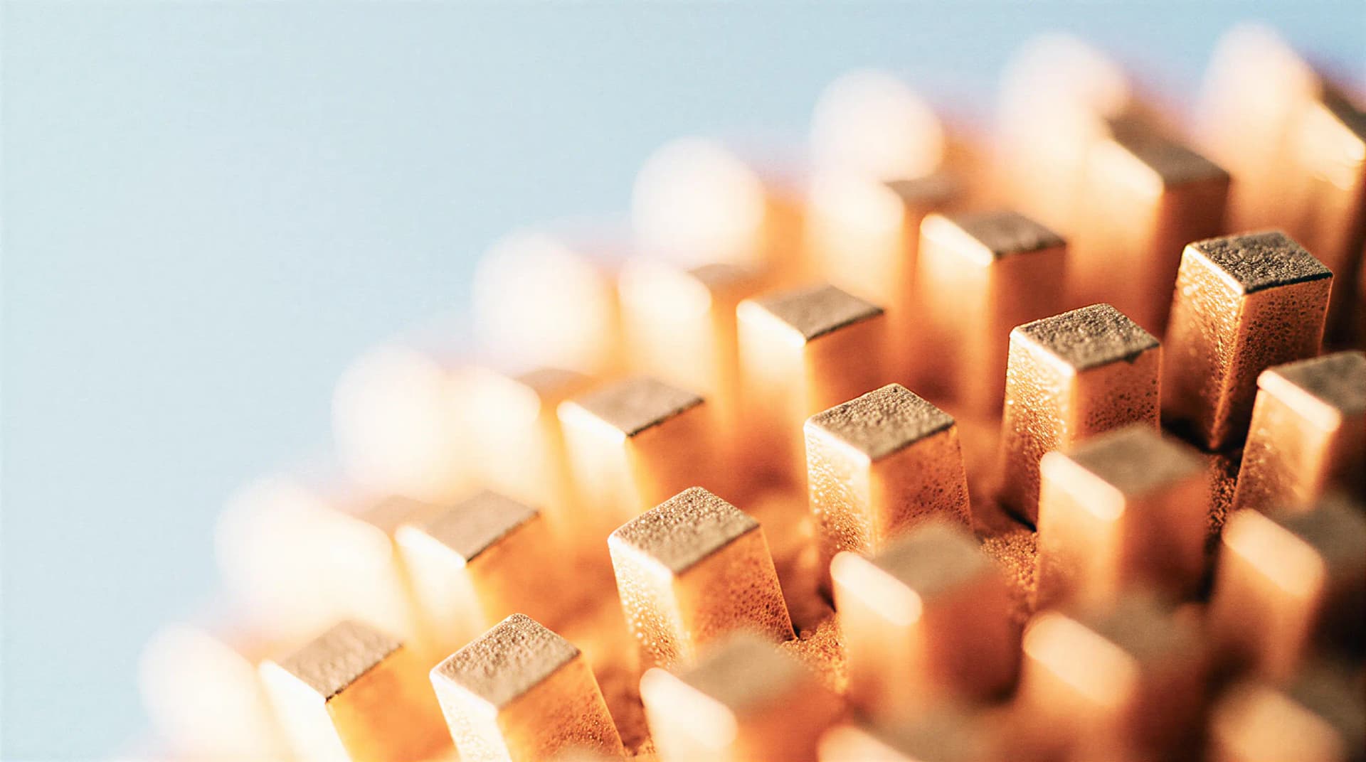 Close-up of copper-colored metal pins in a grid pattern against a blurred blue background.