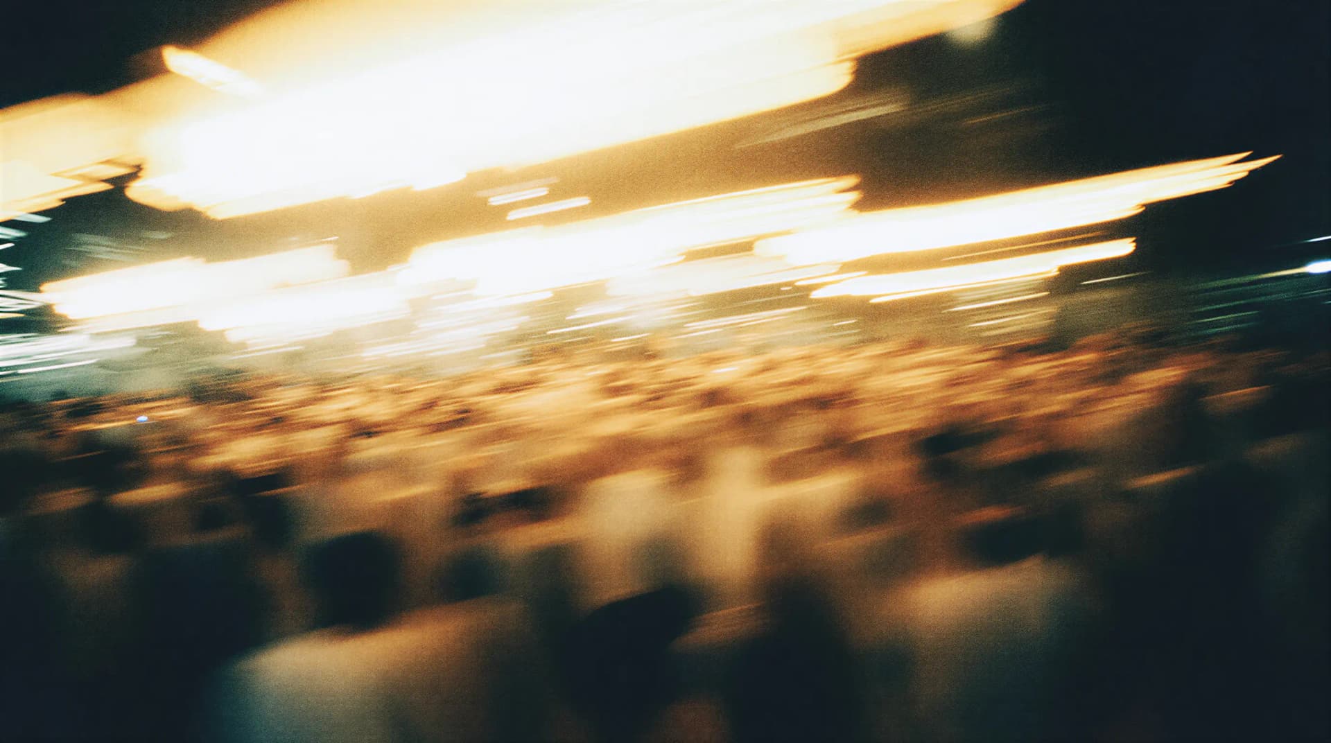 Abstract motion blur of a crowded scene with bright lights and dark background, creating a dynamic and vibrant atmosphere.