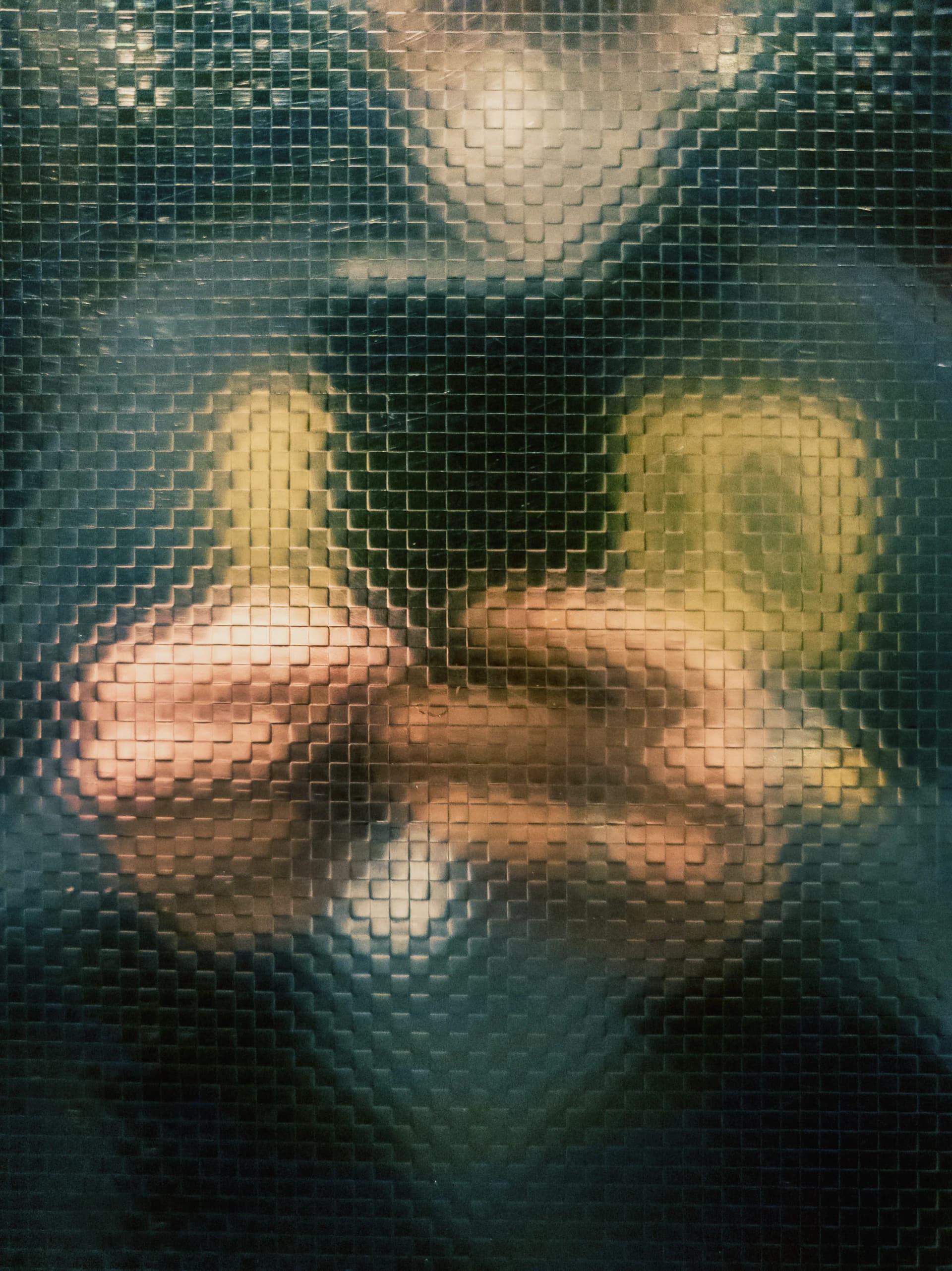 Blurred figure and hands behind textured glass, creating a distorted and abstract visual effect.