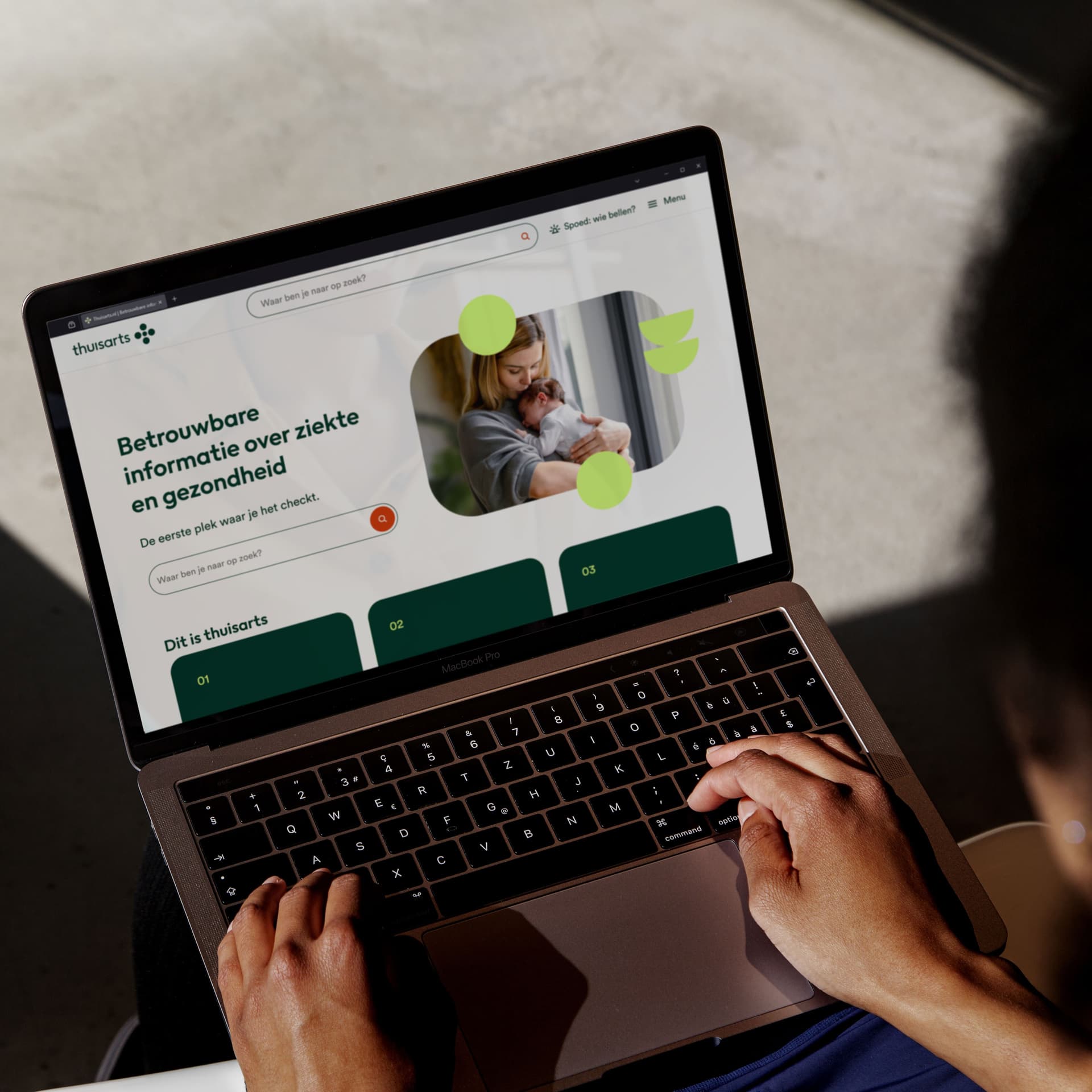 A person using a laptop displaying a healthcare website, featuring a woman holding a baby and text in Dutch about reliable health information.