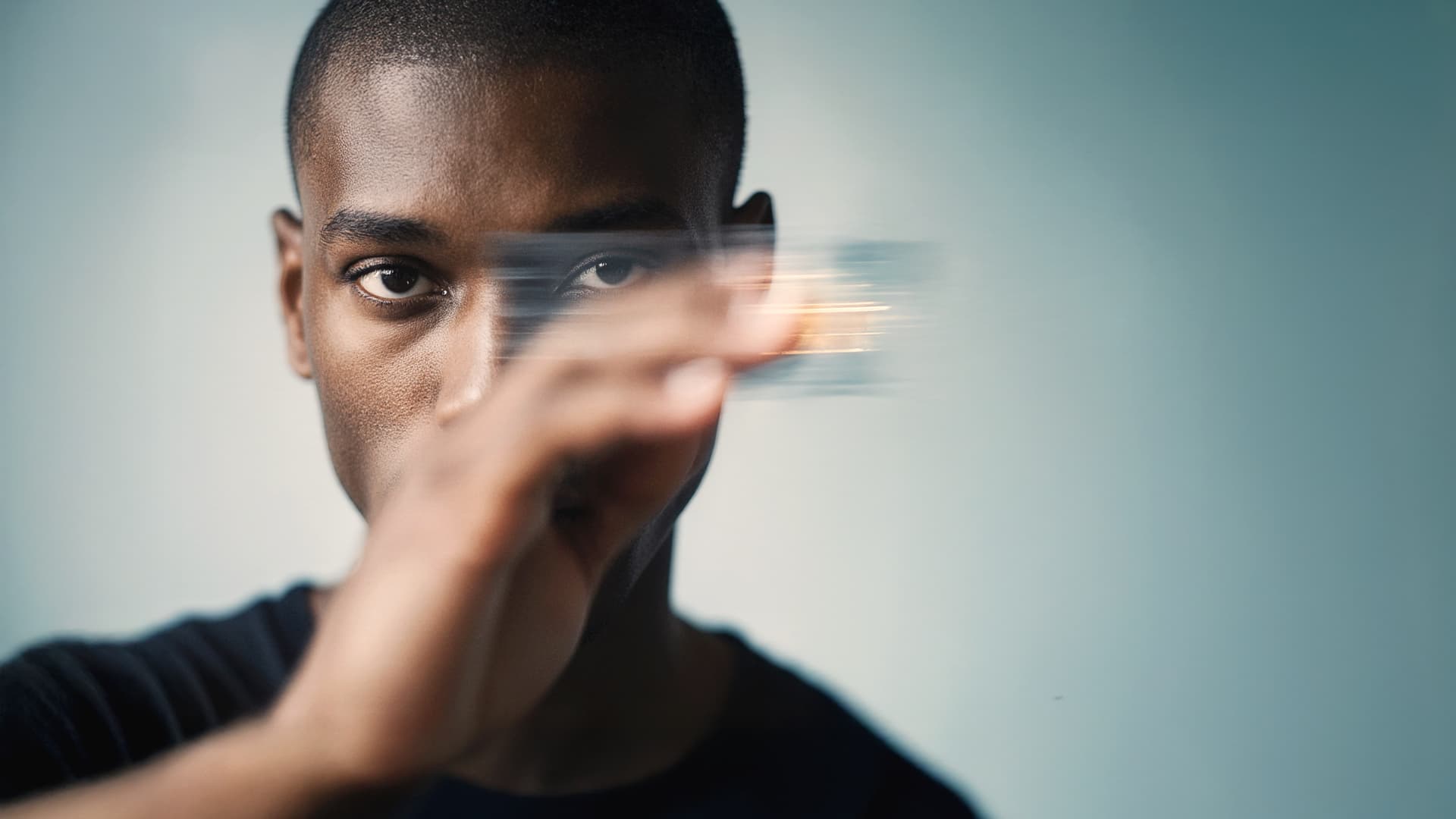 Person holds and moves a blurred credit card in front of their face against a blue background.